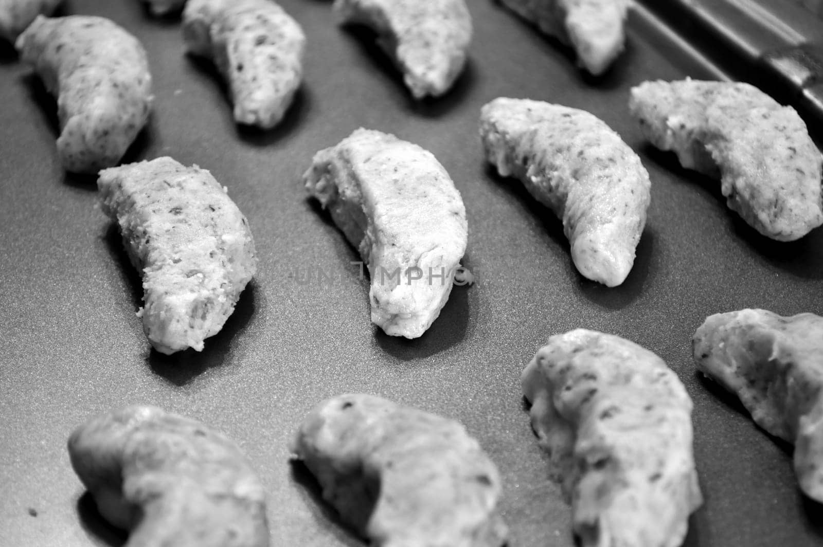 Raw cookie dough, on baking sheet ready to go in the oven. Crescent cookies in moon shapes.