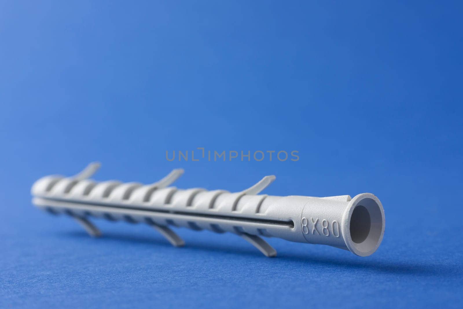 Plastic straddling dowel or rawl plug on a blue background