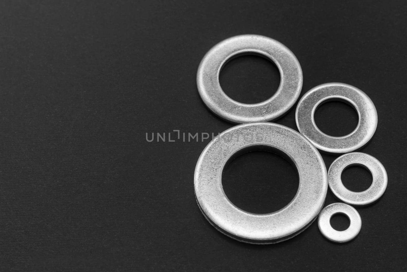 Pile of stainless steel flat washers isolated on a dark background