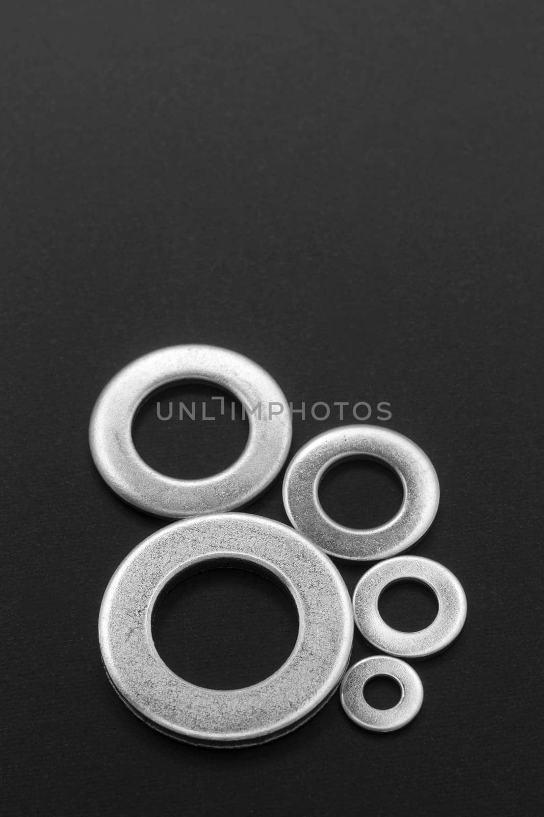 Pile of stainless steel flat washers isolated on a dark background