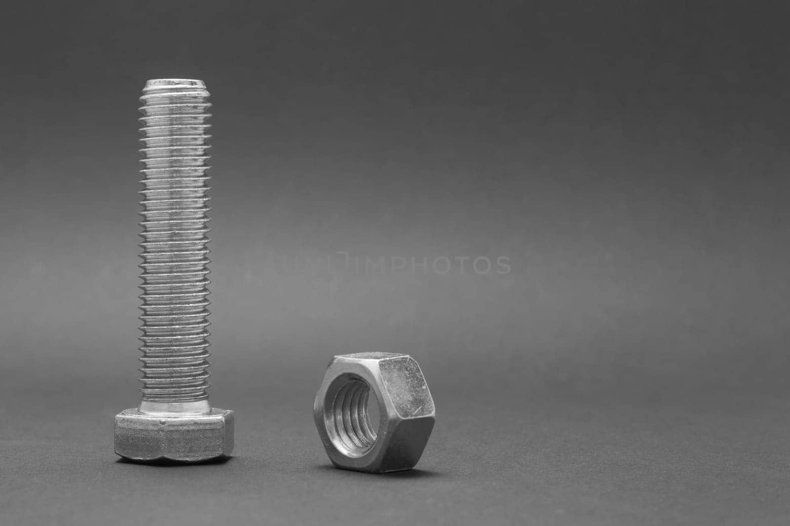 Closeup shiny steel bolt with nut on the black background