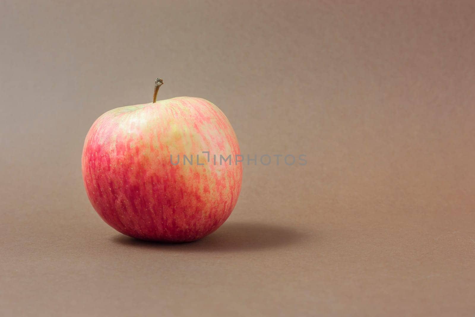 Ripe red apple on a brown background