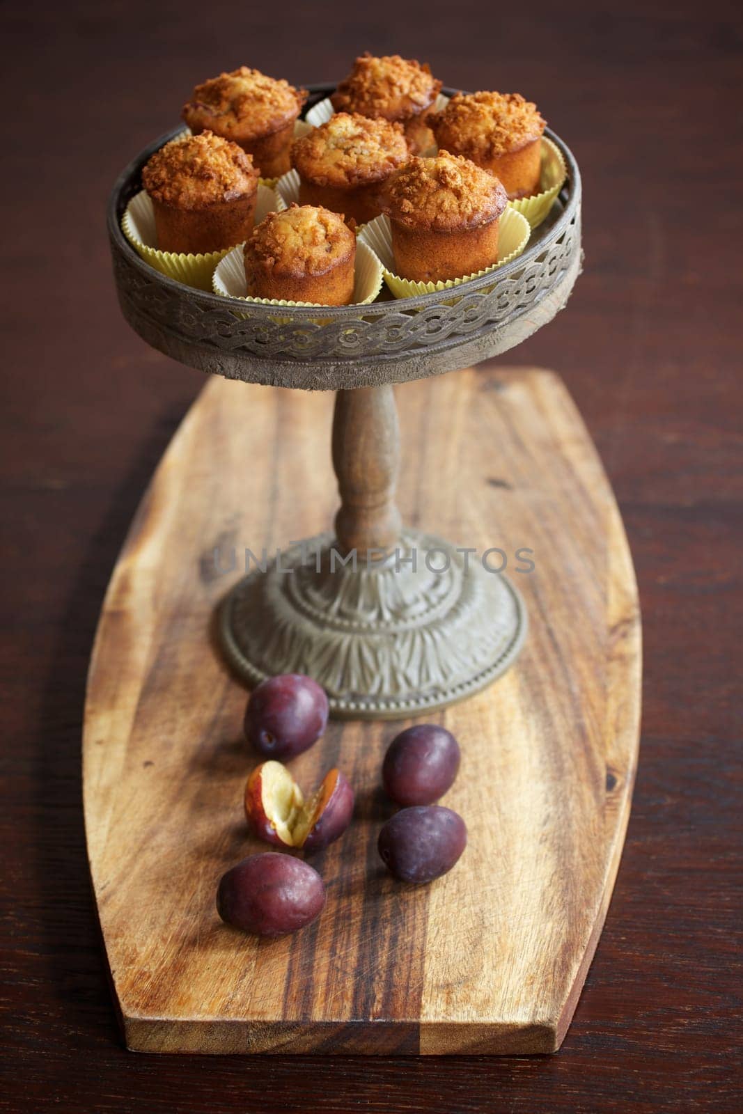 Plum muffins on cake stand with some plums