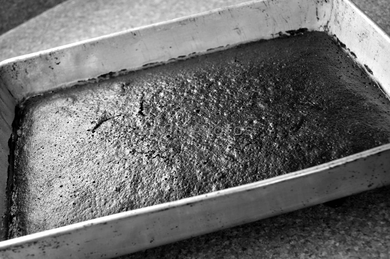 Freshly baked chocolate cake, in black and white. Sheet cake in pan just taken out of the oven.
