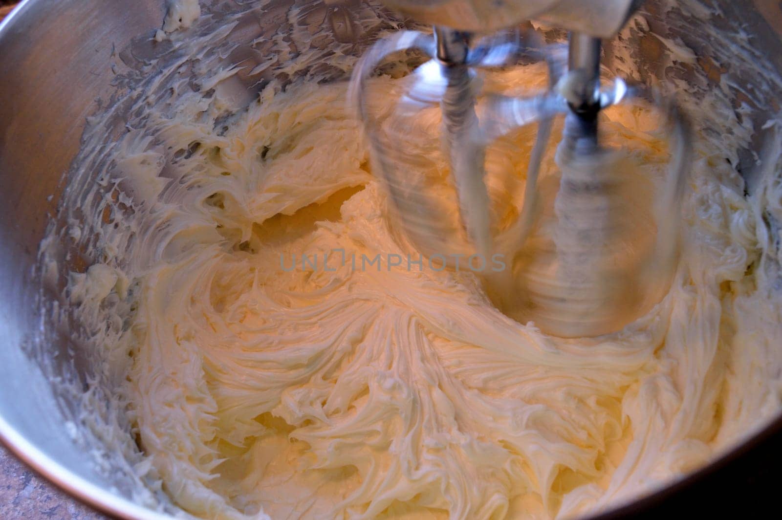 Stainless steel stand mixer at high speeding whipping homemade icing ingredients together.