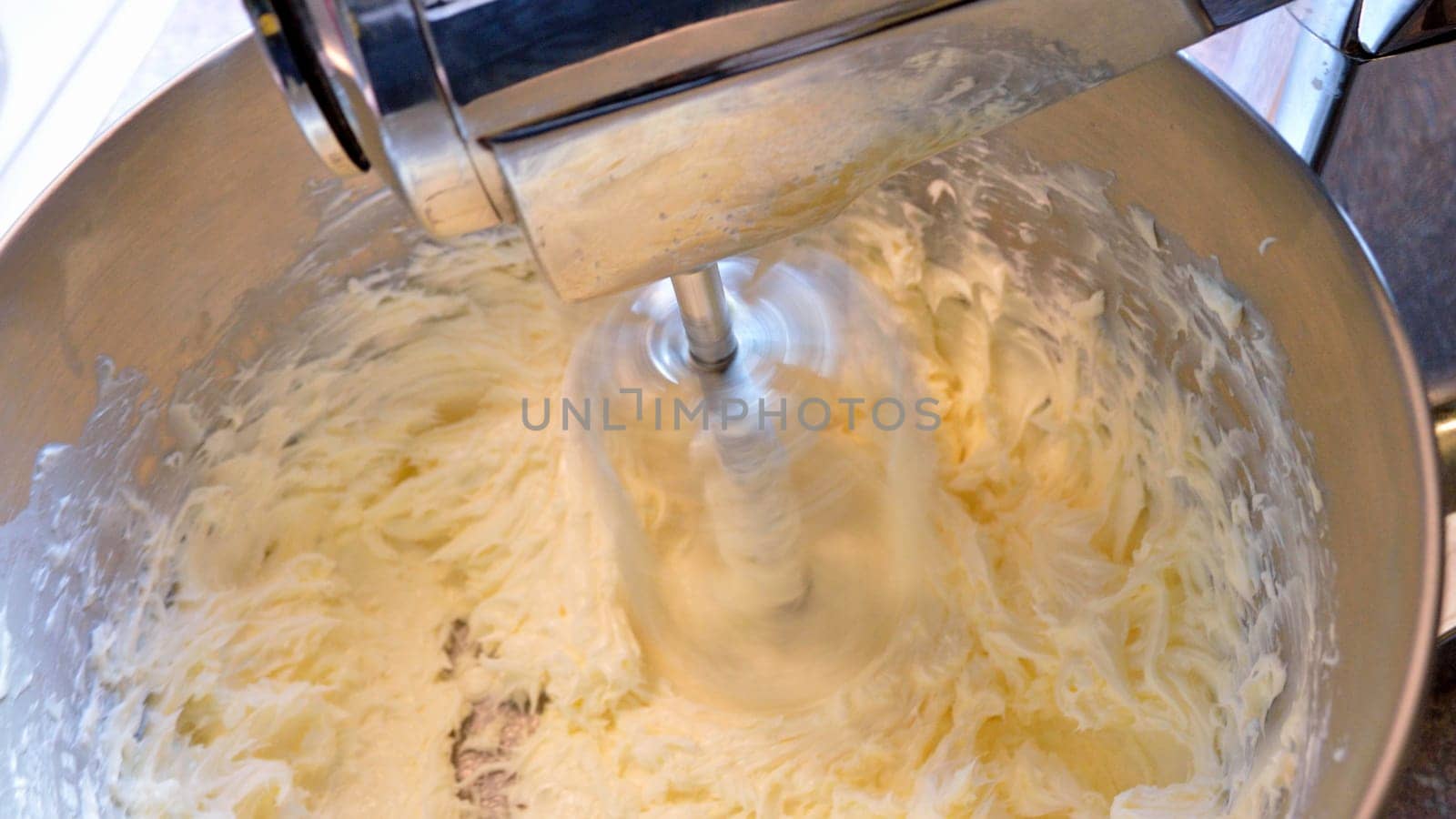 Stainless steel stand mixer at high speeding whipping homemade icing ingredients together.