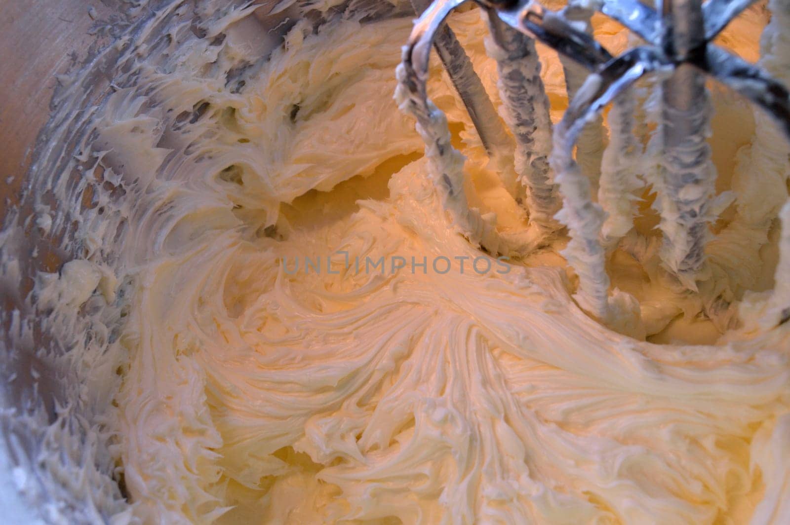 Yummy, homemade, vanilla icing in stainless steel stand mixer after having been mixed together.