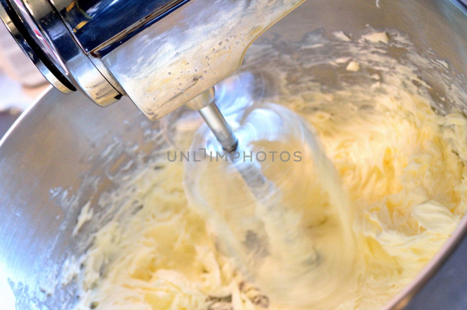 Stainless steel stand mixer creaming butter at high speed.