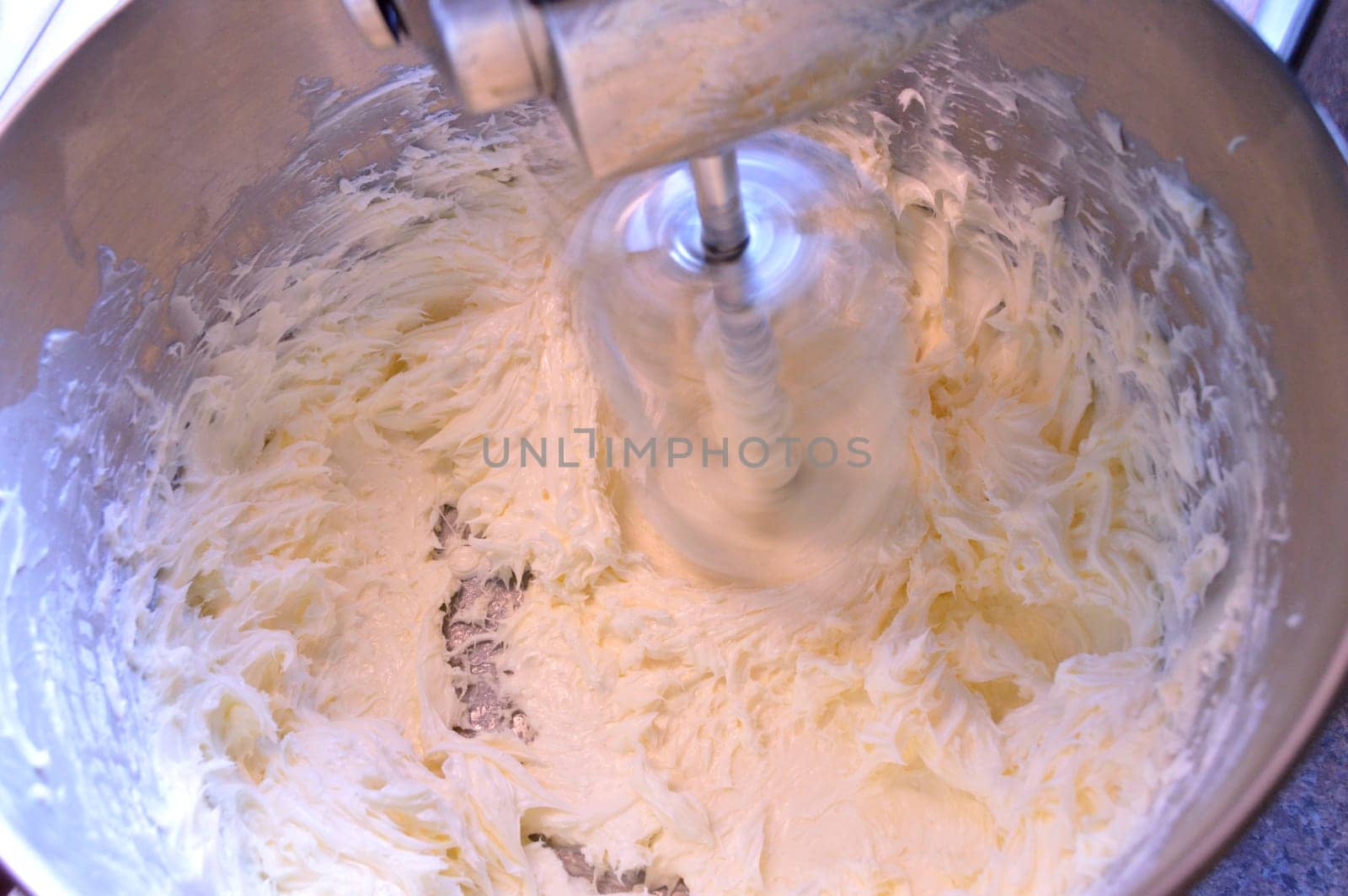 Stainless steel stand mixer at high speeding whipping homemade icing ingredients together.