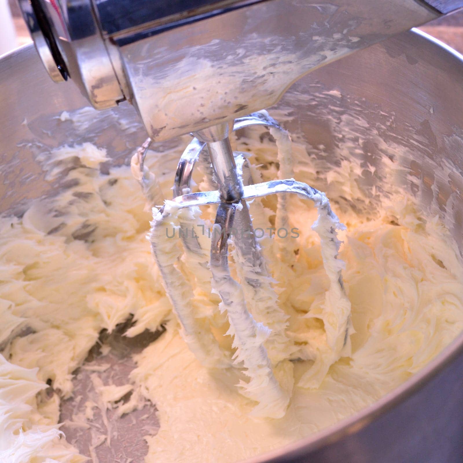 Square image of creamed butter in a stainless steel stand mixer. Butter creamed for use in baking and icings.