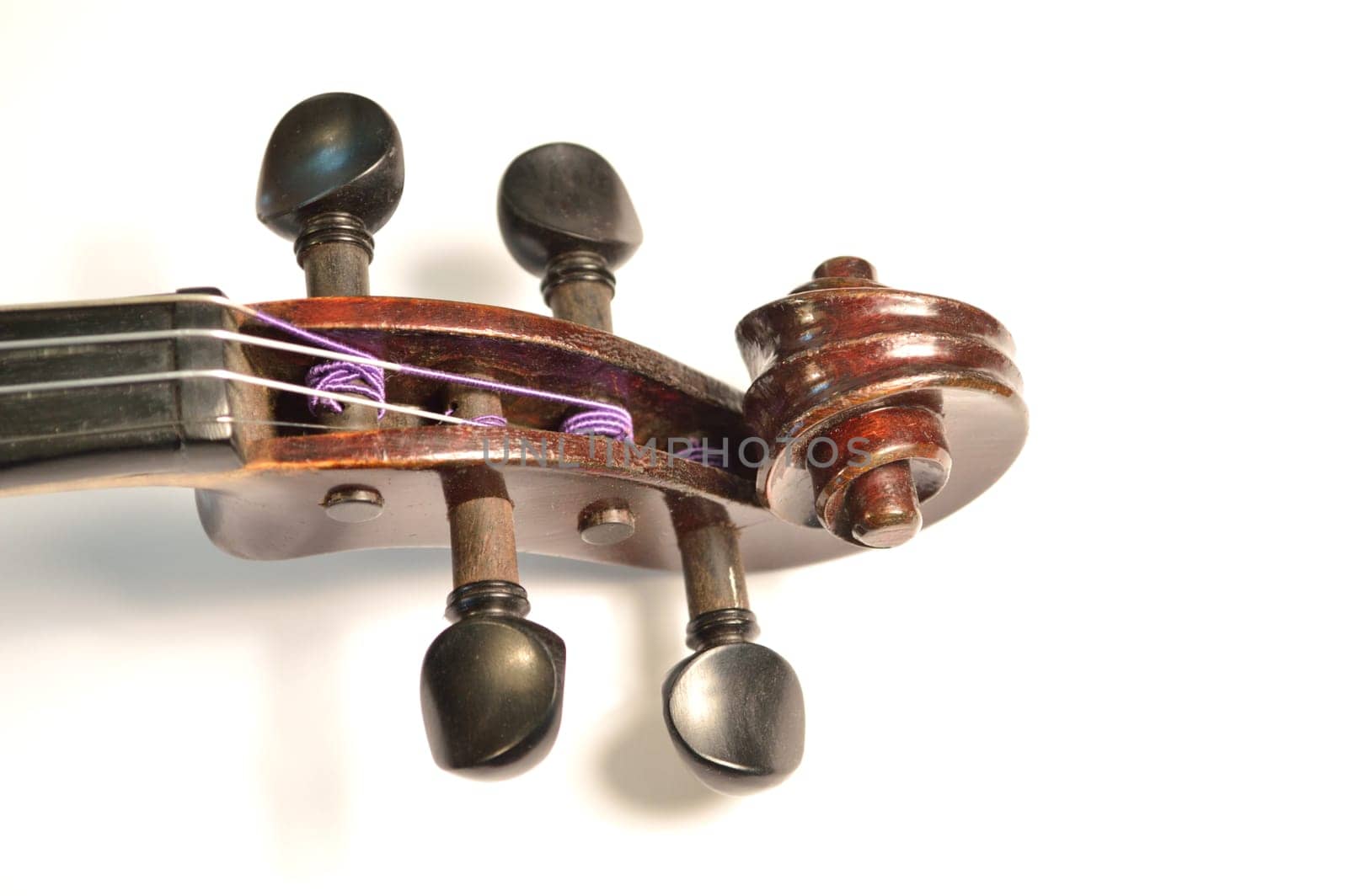 Scroll of an antique violin against a bright white background. Violin is an antique from the early 1800's in a dark stain (original finish).