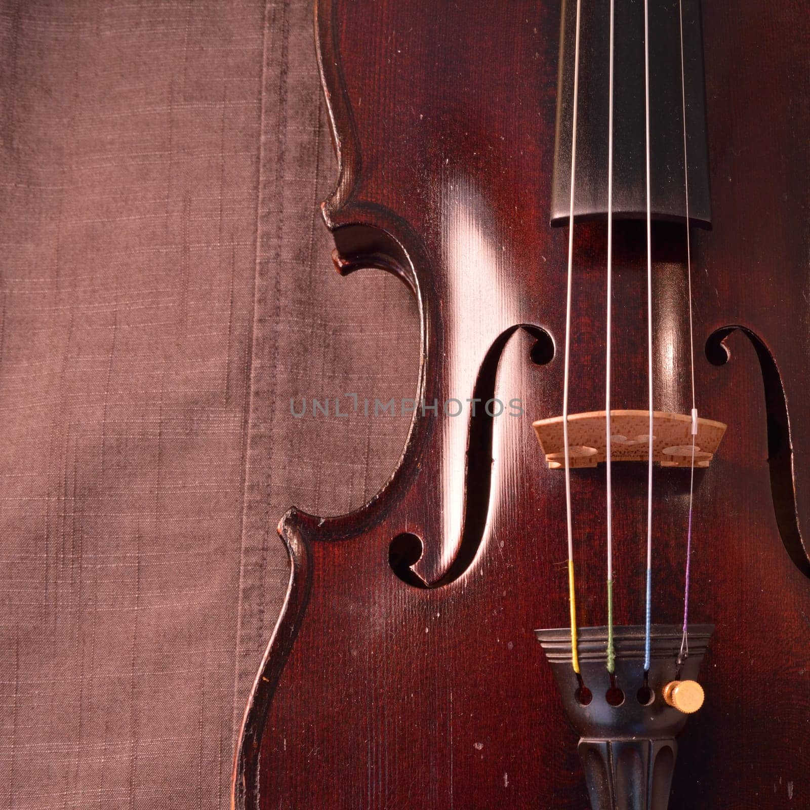 Old violin against gray seamed fabric. Violin is an antique from the early 1800's in a dark stain (original finish). Square image with copy space.