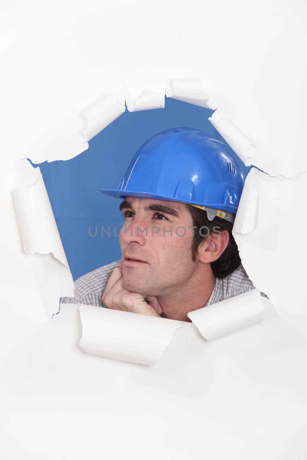 craftsman looking through a hole in a paper wall