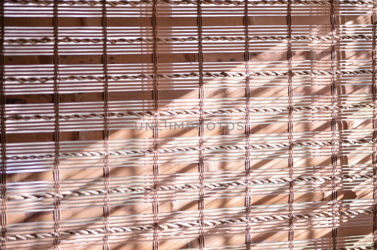 Bamboo shades covering window with sunlight shining on them