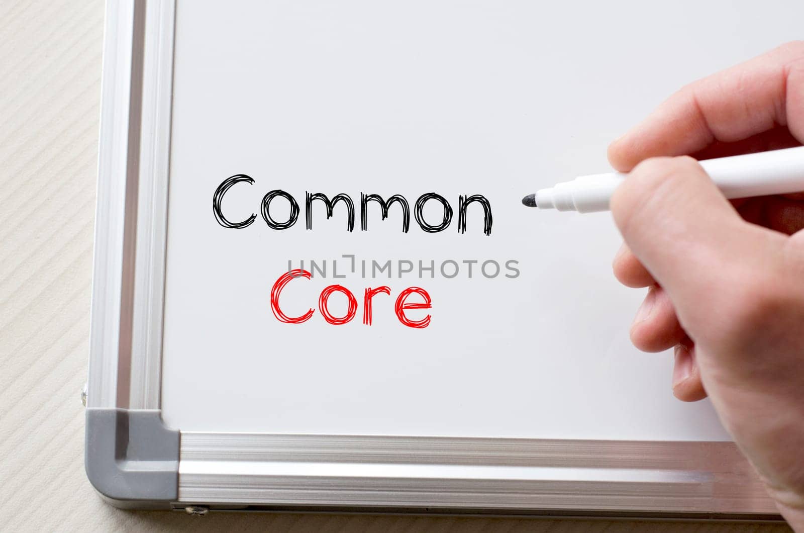Human hand writing common core on whiteboard
