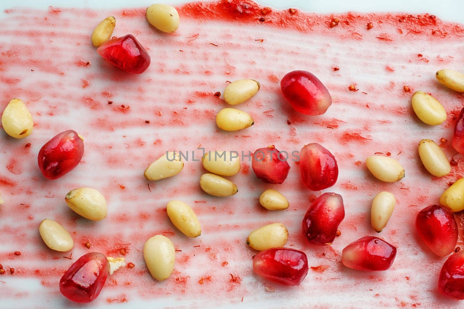 appetizing restaurant food - pomegranate and cedar seeds on  white background