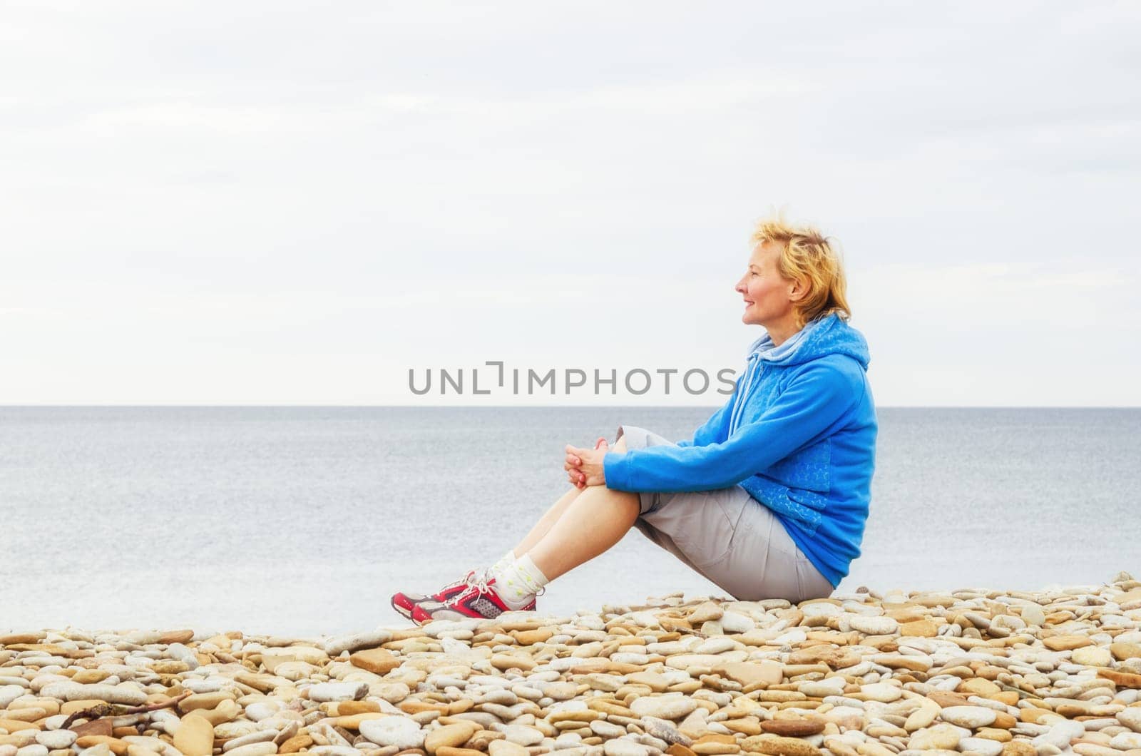 Woman sitting on the beach and looks into the distance