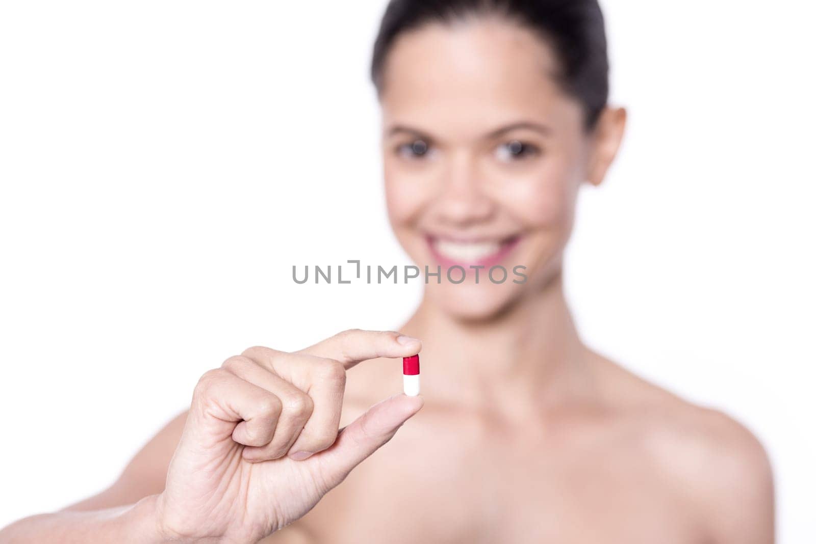 Focused image of spa woman showing vitamin pill