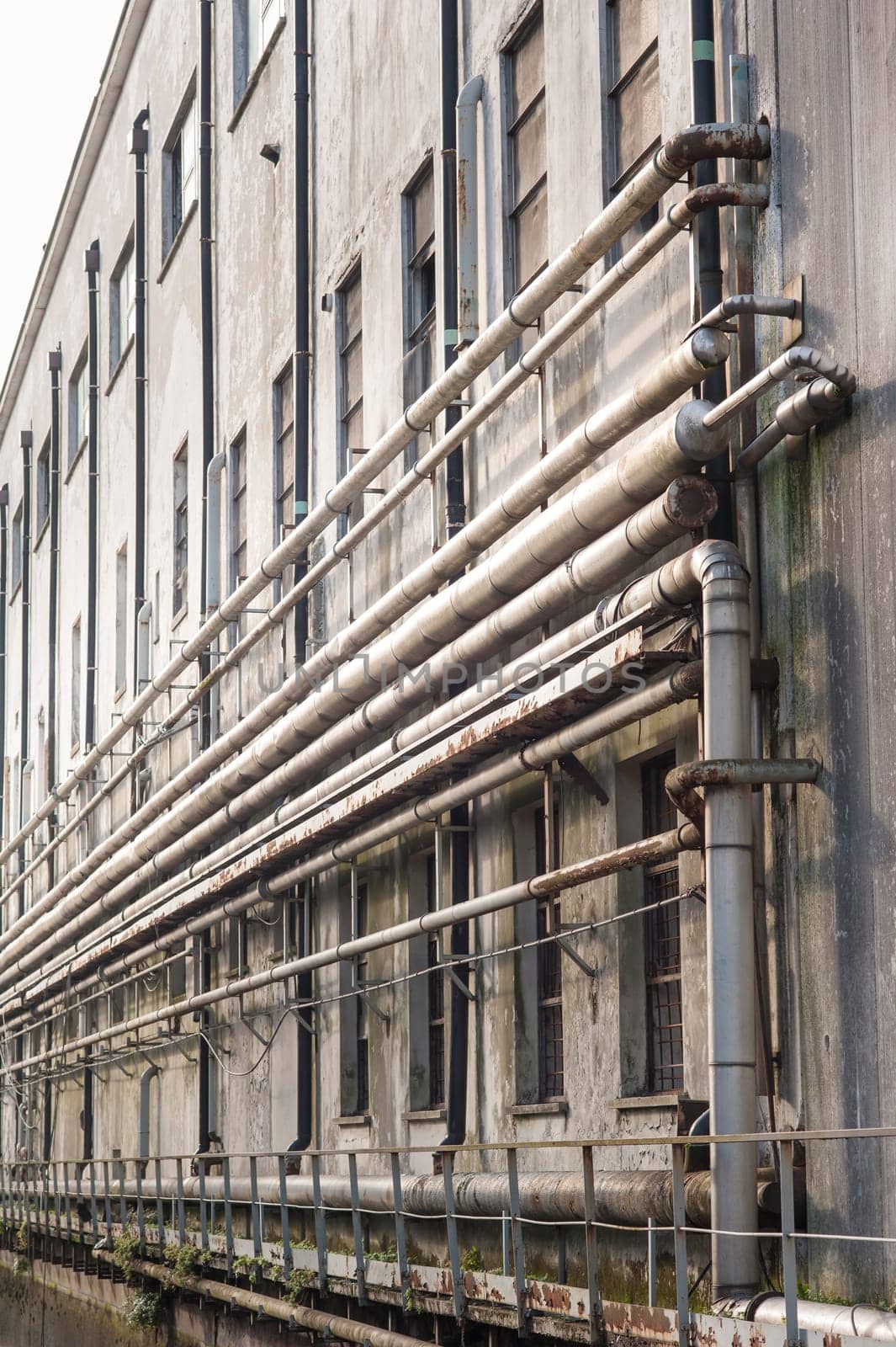Old pipes on the wall outside of an old abandoned factory.