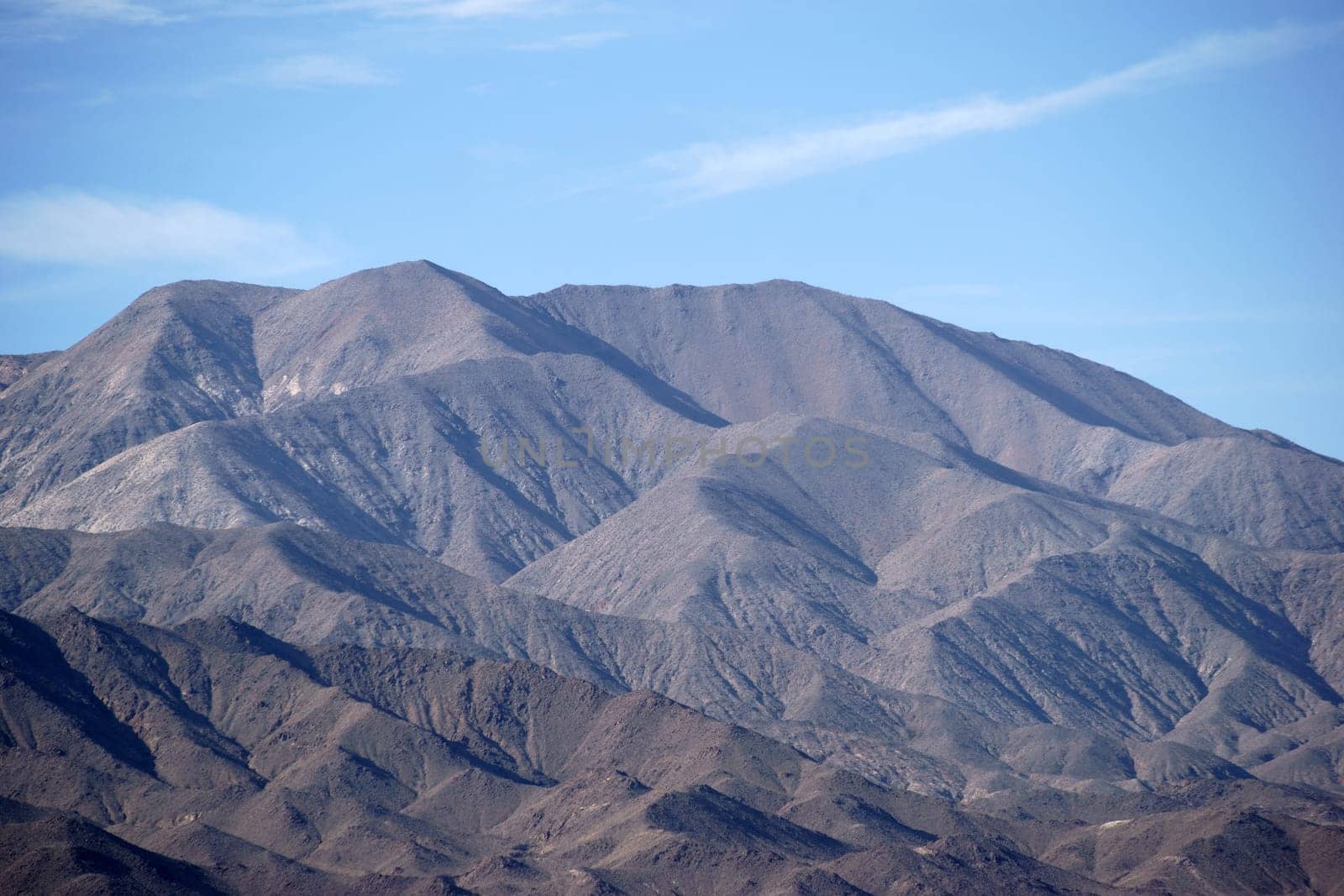 The portrait of a mountain with different and dark rock layers and faults near the Death Valley intersection.