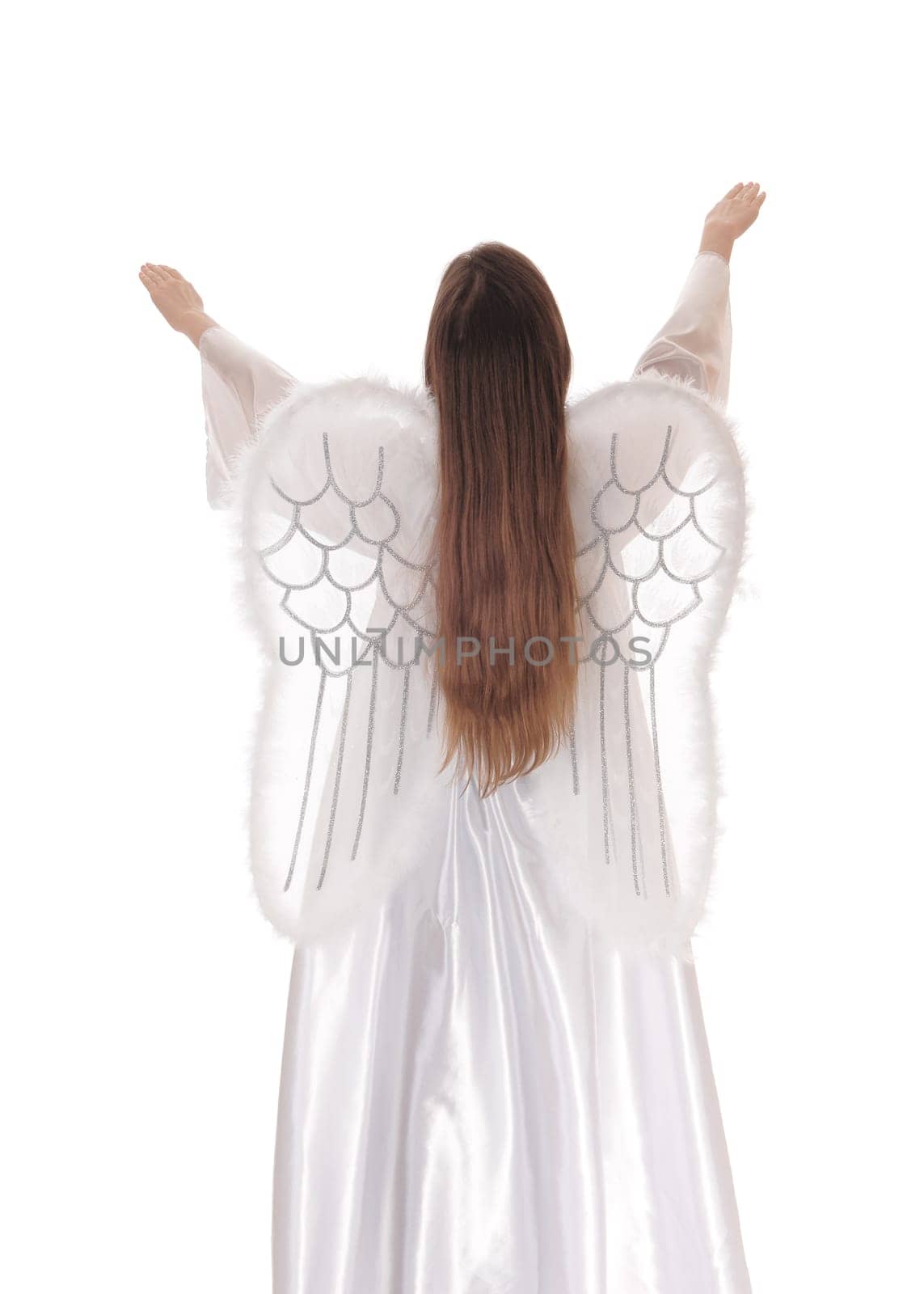 An angel in a long white satain dress with wings and long brown hair standing .from the back with both arms raised isolated for white background..