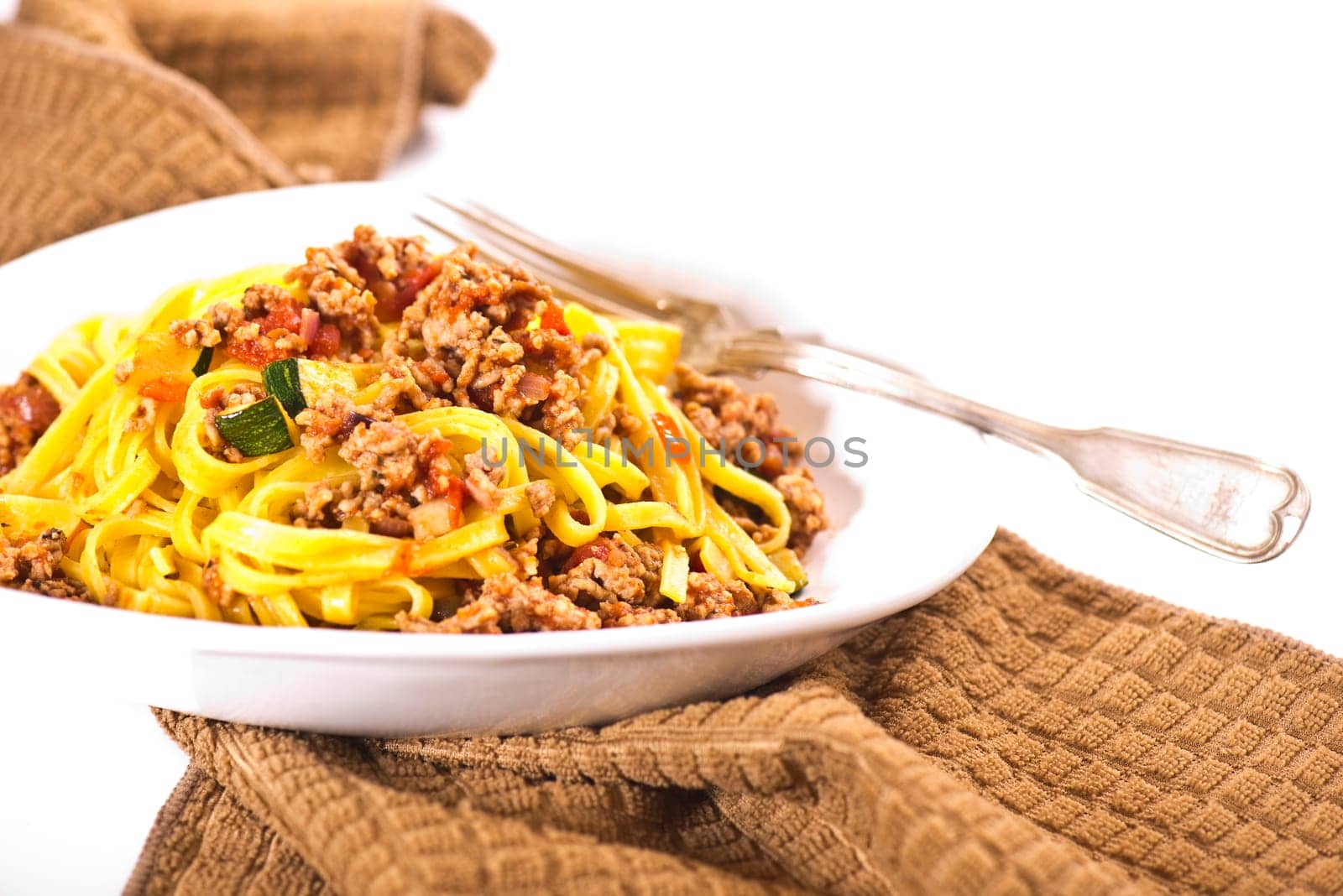Ribbon noodles with minced meat in white peel with peppers and herbs