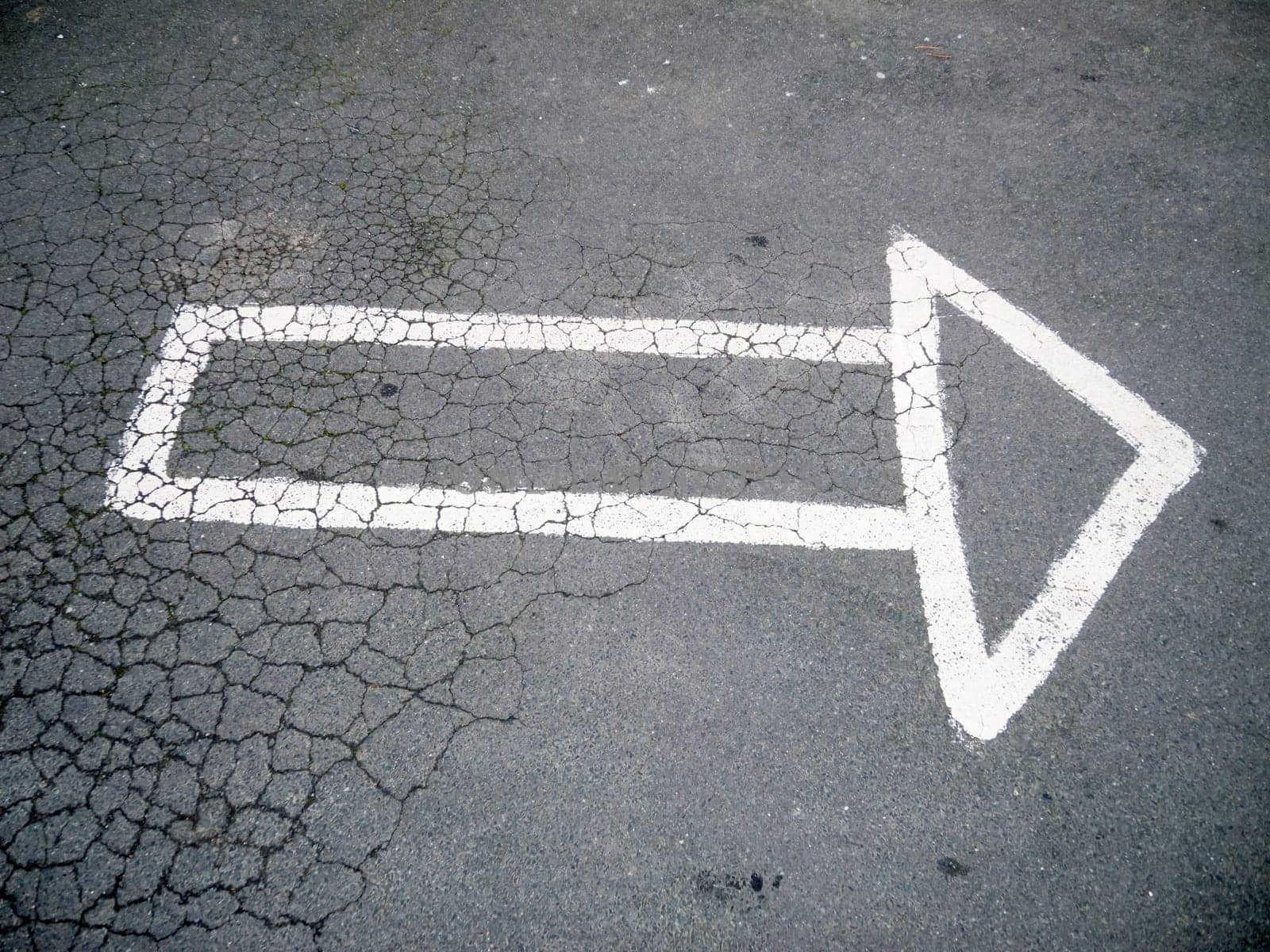 An arrow outline painted by hand on the asphalt to the right.