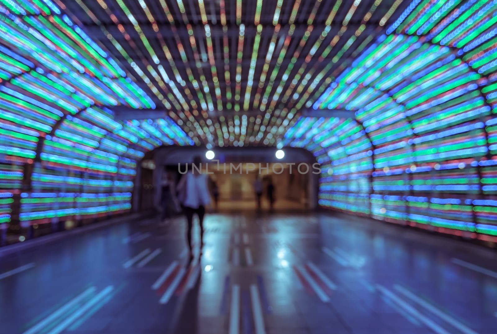 Blur abstract bokeh of colorful LED light tunnel with walking people