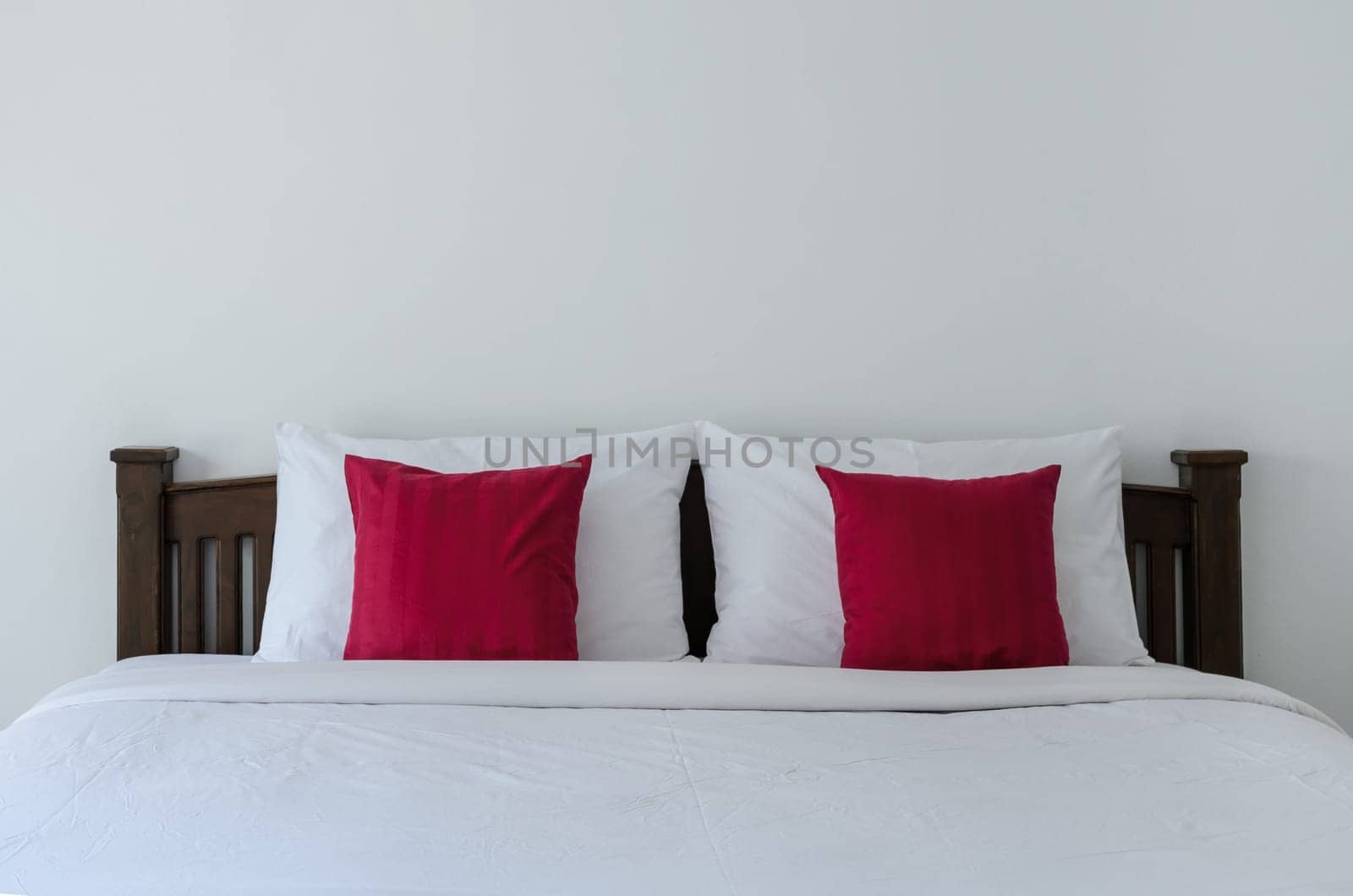 White bedroom with tidy King size bed and red pillows