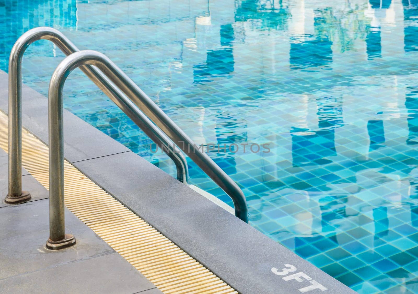 Swimming pool with metal handrail stair