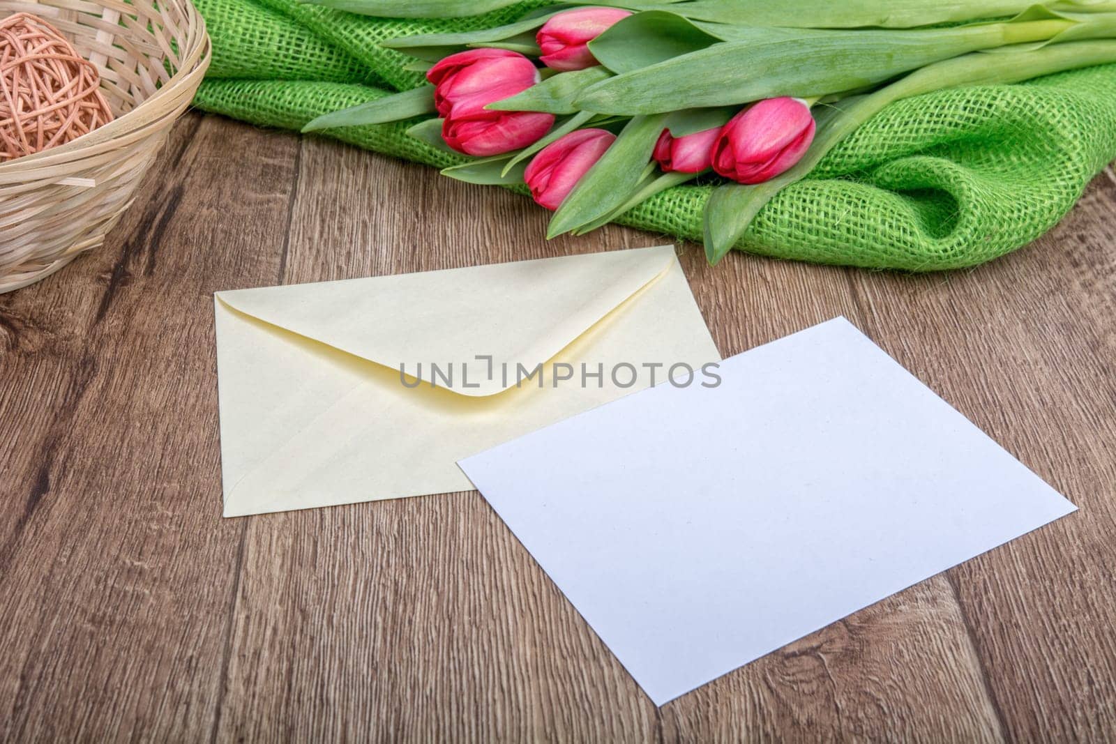 Envelope with sheet of paper and red tulips on a wooden background
