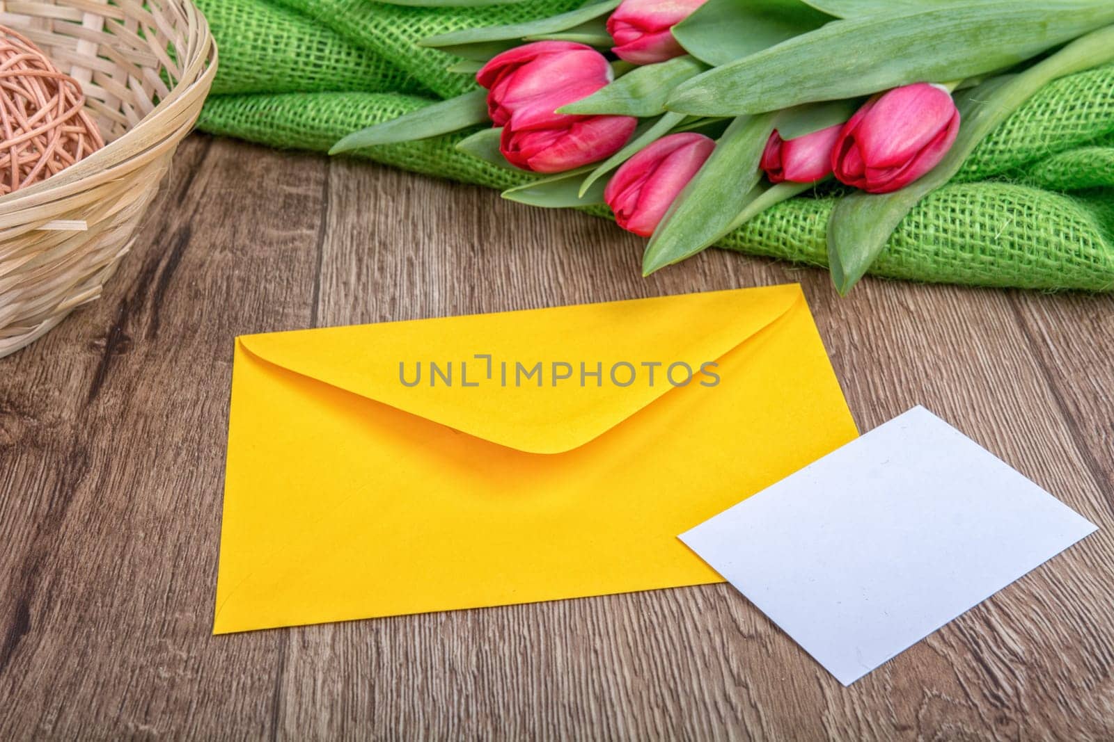 Envelope with sheet of paper and red tulips on a wooden background