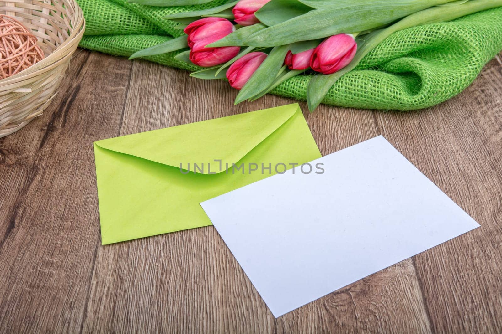 Envelope with sheet of paper and red tulips on a wooden background