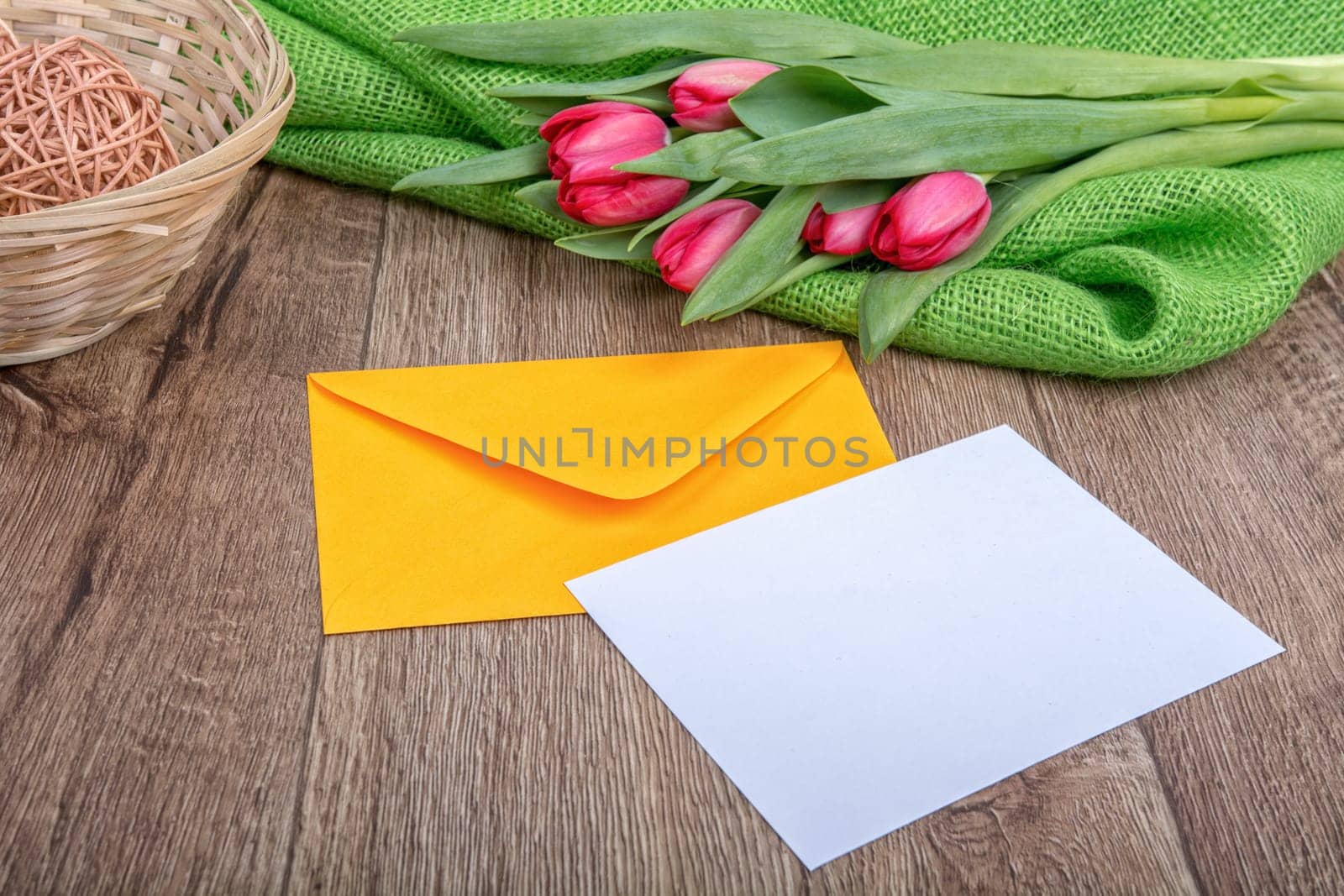 Envelope with sheet of paper and red tulips on a wooden background