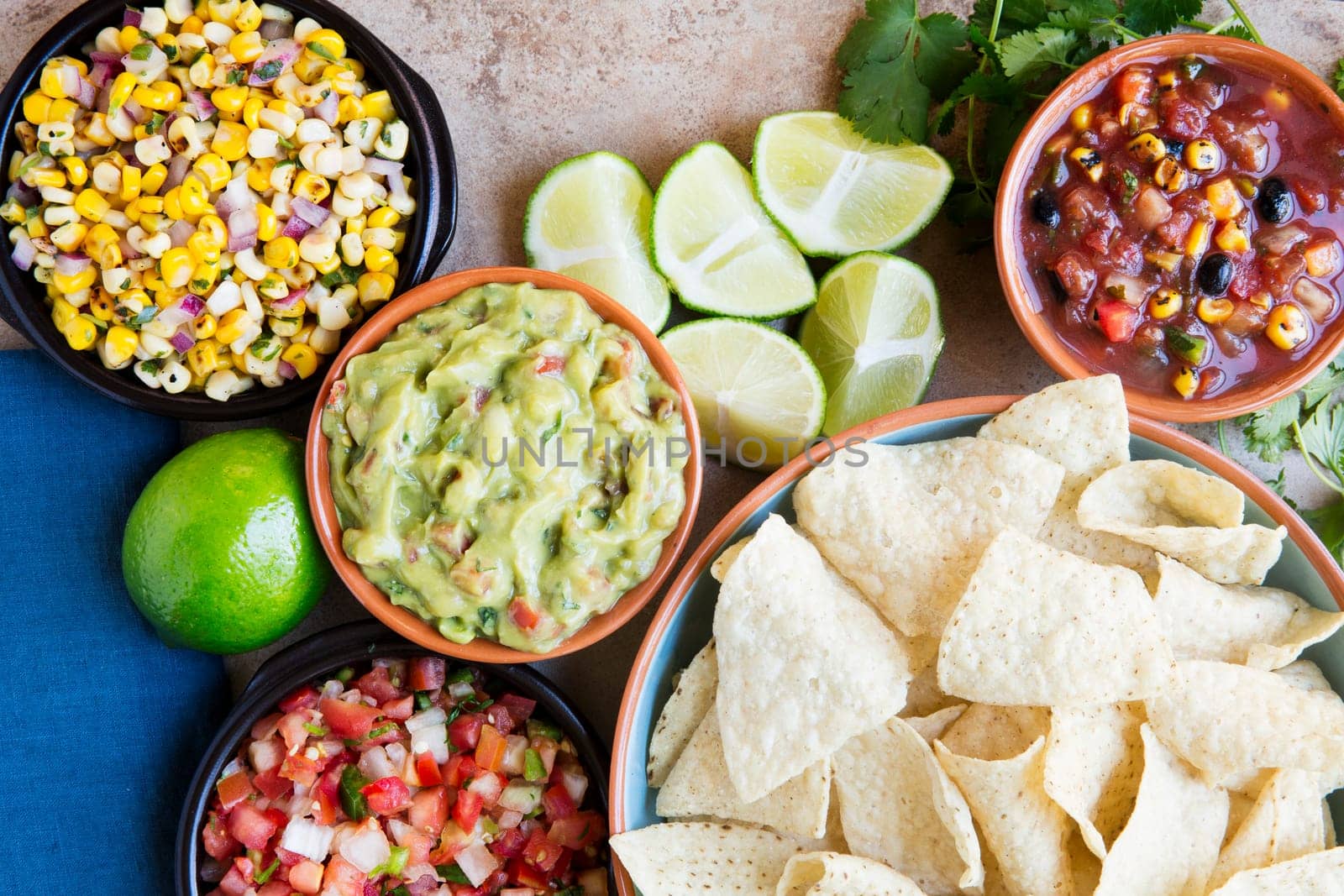 Tortilla chips served with guacamole, salsa, and pico de gallo, view from above.