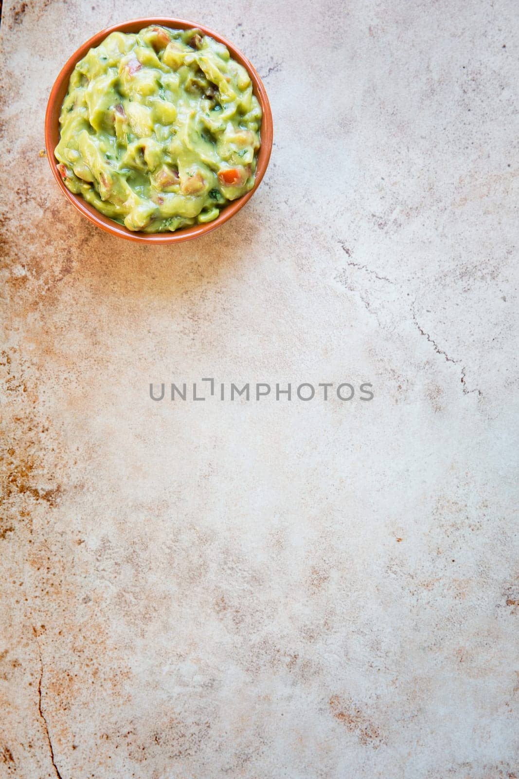 Bowl of fresh guacamole  n stone surface with copy space and viewed from above.