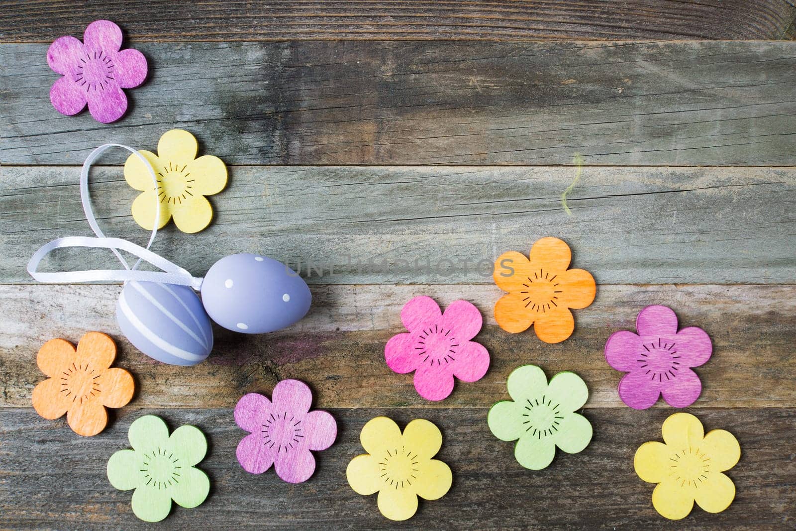 Easter Eggs and wooden flowers on wooden table with copy space.