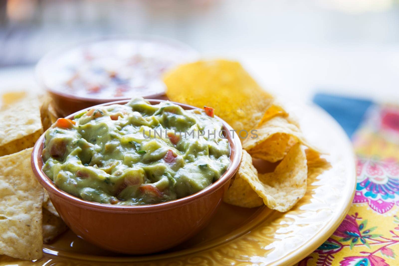 Fresh guacamole in a bowl with tortilla chips