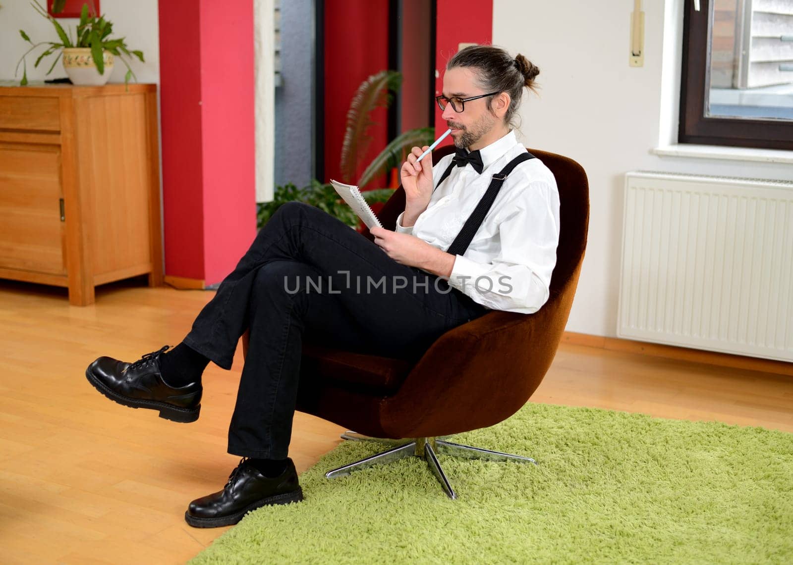 young bearded man in white shirt with bow-tie writing