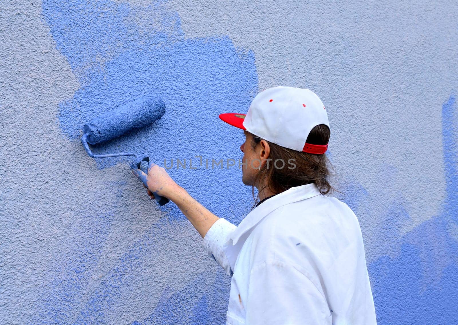 workman painting the wall with paint roller