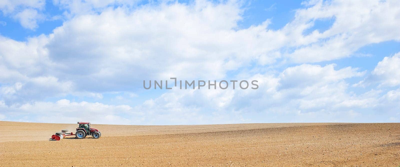 Farm work. Tractor compresses the soil after planting with rollers.