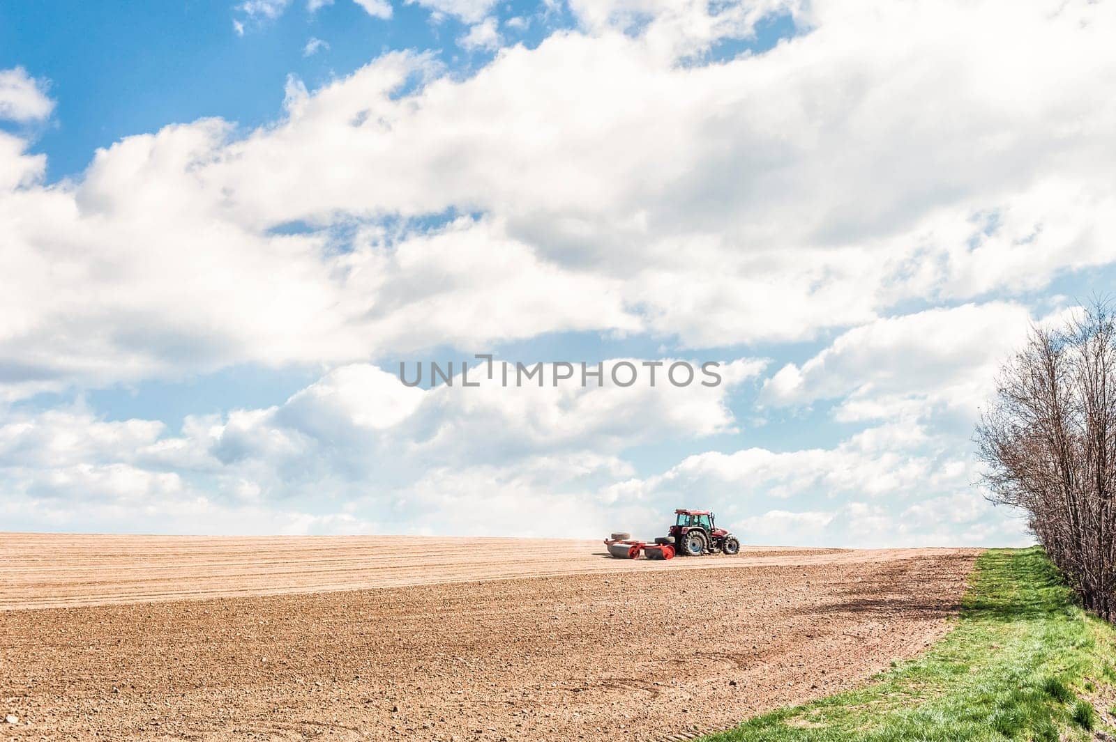 Farm work. Tractor compresses the soil after planting with rollers.