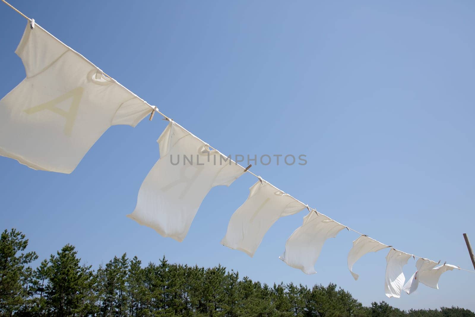 White laundry hanging on the clothesline against blue sky