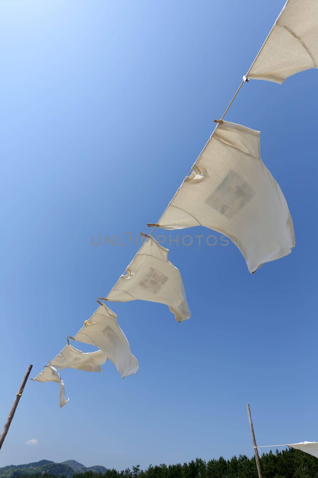 White laundry hanging on the clothesline against blue sky