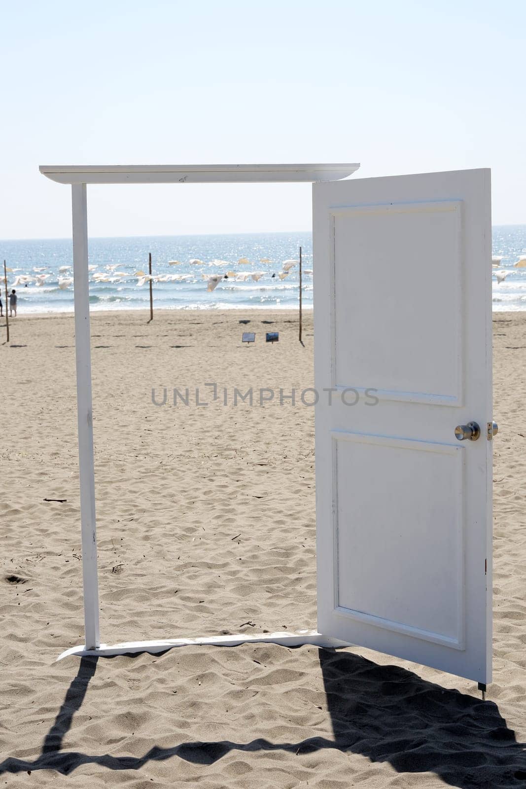 White door on the beach, opened to a view of coast