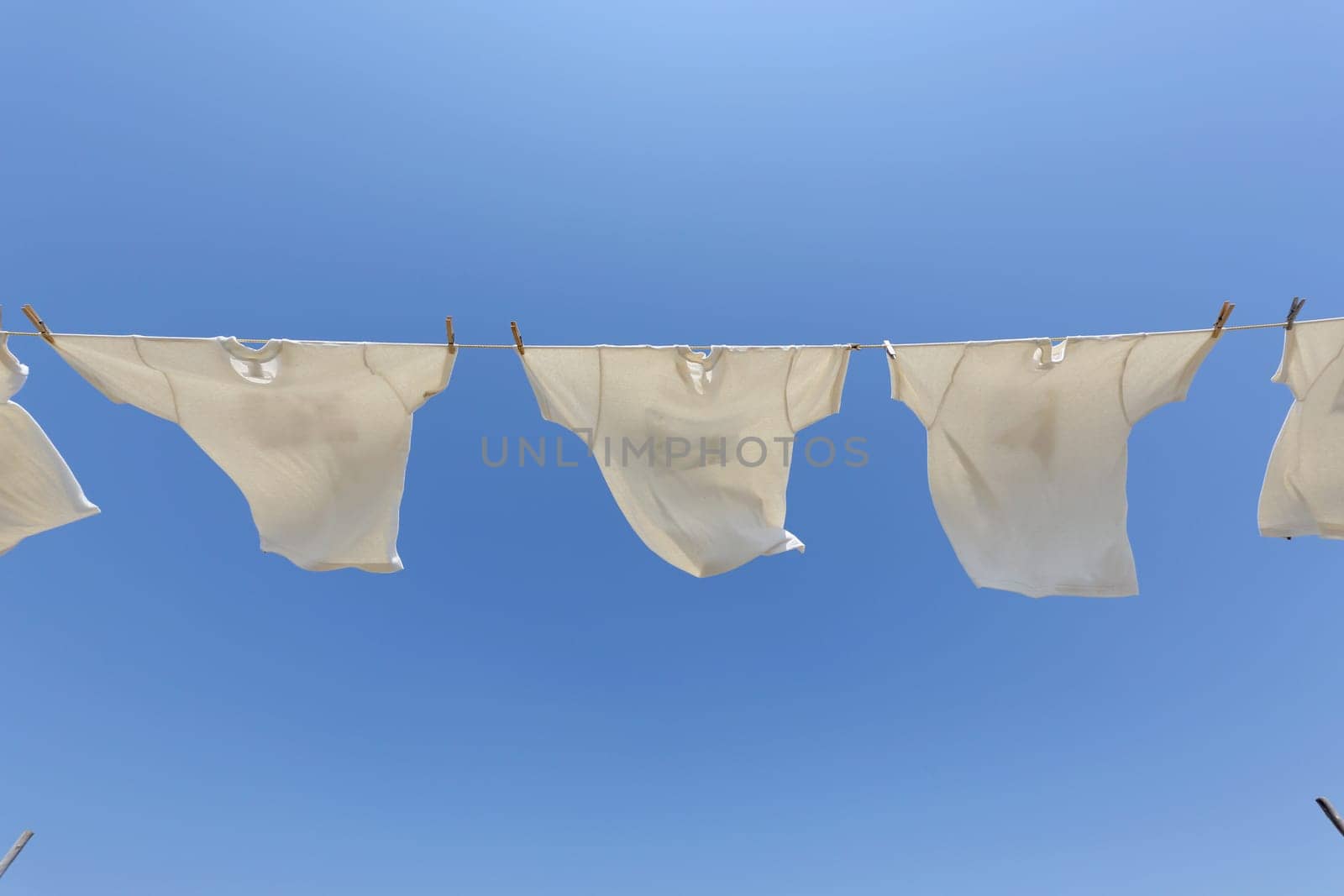 White laundry hanging on the clothesline against blue sky
