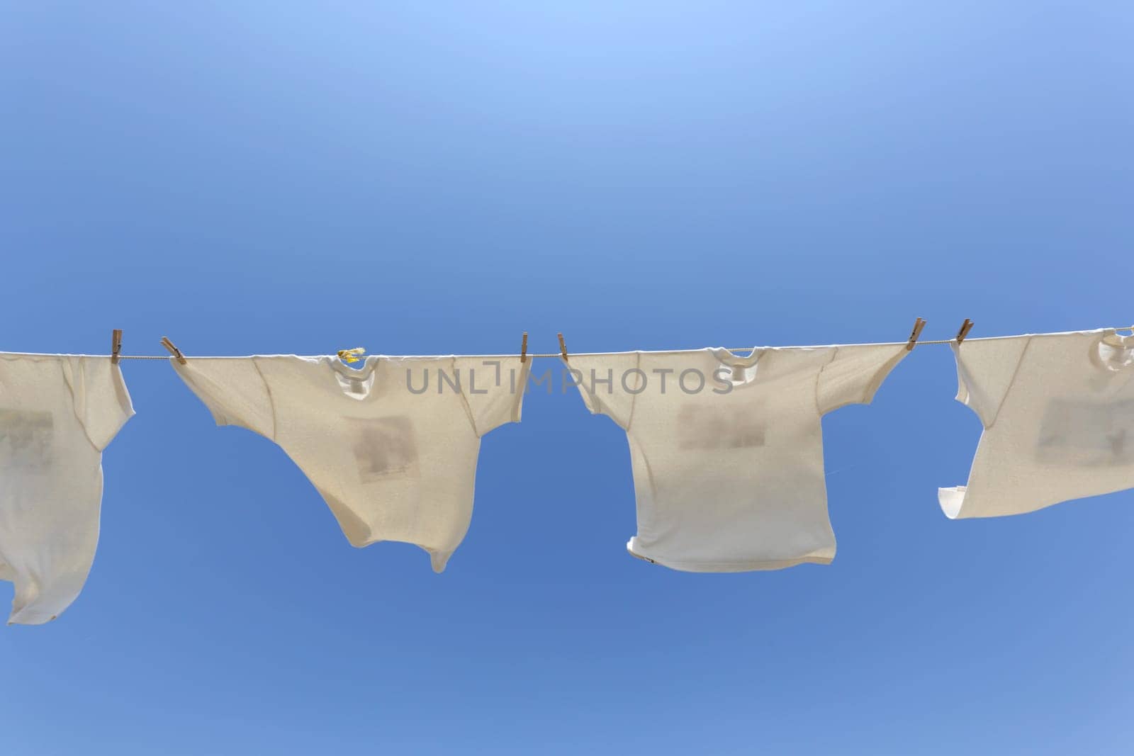 White laundry hanging on the clothesline against blue sky