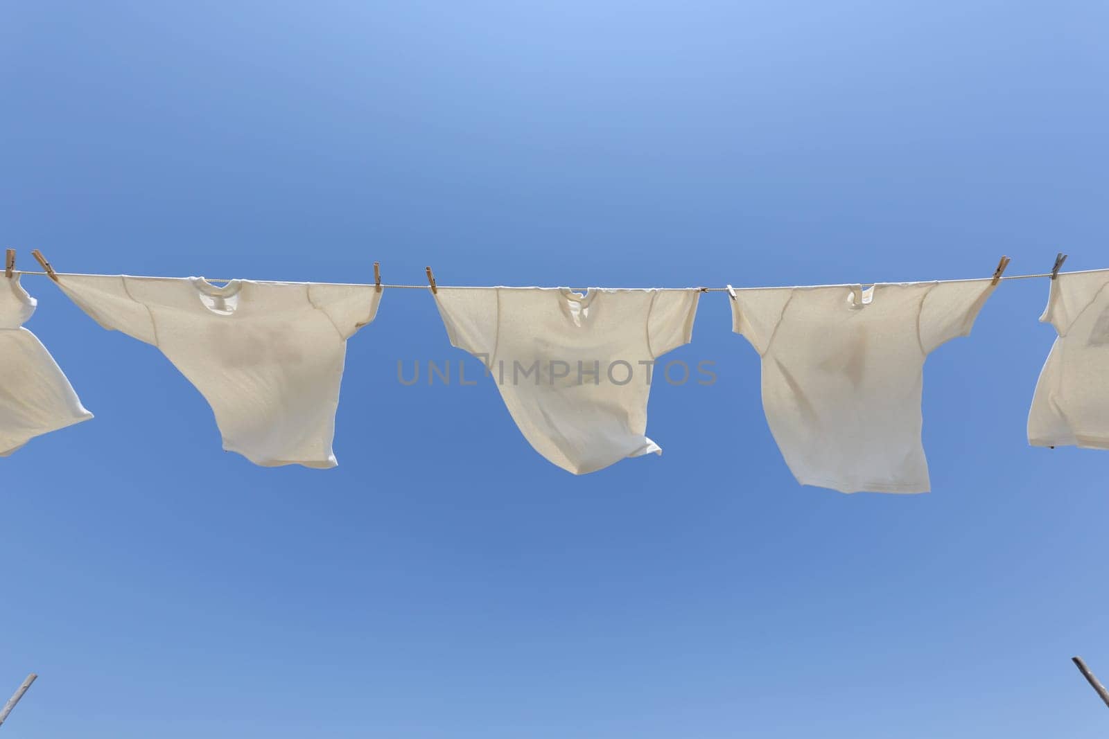 White t-shirts hanging on the clothesline against blue sky
