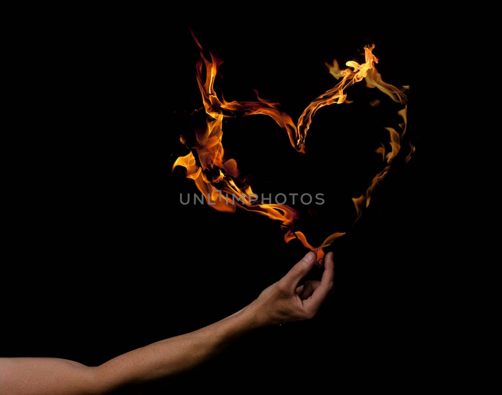 Hand holding heart shaped flames on a dark background