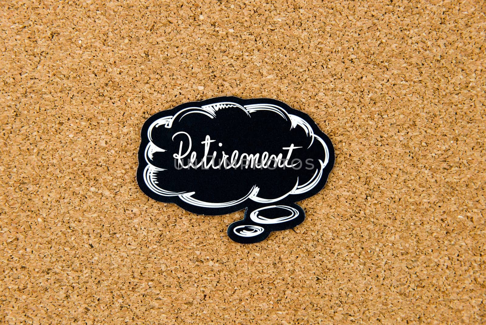 RETIREMENT written on black thinking bubble over cork board background, copy space available
